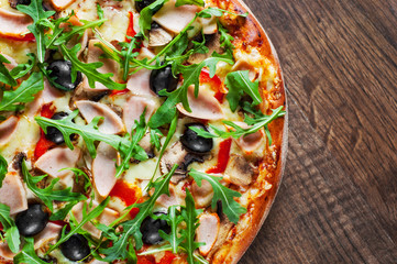 Pizza with Mozzarella cheese, mushrooms, ham, tomato sauce, pepper, olives, Spices and Fresh arugula. Italian pizza on wooden table background