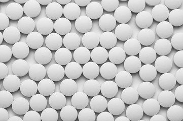 Small white pills on a white background close-up.