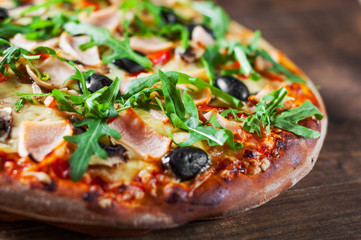 Pizza with Mozzarella cheese, mushrooms, ham, tomato sauce, pepper, olives, Spices and Fresh arugula. Italian pizza on wooden table background