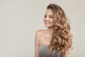 Fototapeta premium woman on a gray background with wavy blond hair. happy smile. The concept of clean skin. copycpase