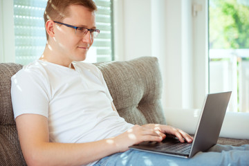 Young male freelancer working with laptop at home