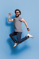 Trendy jumping hipster on blue backdrop 