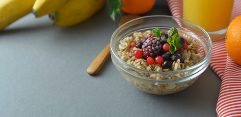 Healthy breakfast in a bowl with oatmeals, frozen berries, fresh strawberries, mint. Oat porridge with fruits. Banner.