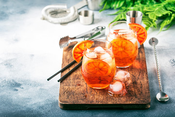 Aperol spritz cocktail in wine glass with sparkling wine, liqueur, ice cubes and red orange -...