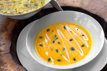 Cream pumpkin soup, on a wooden board. against a background of chicken soup.