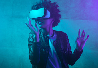 Contemporary woman in VR headset in neon light 