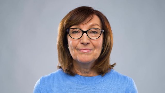 communication, age and people concept - happy senior woman in glasses having video chat or interview over grey background