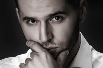 portrait of a pensive businessman in a white shirt on a black background