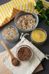 Brown flax seeds, closeup in glass bowl with variouse cereals on the background. Healthy food for breakfast, cereals. Food ingredient.