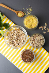 Various uncooked cereals. Different types of groats in bowls on gray background, top view, close up. Healthy nutrition food