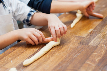 Young children make hot dog. Hands closeup