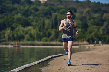 A male runner runs along the road to the park.