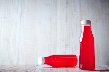 bottled berry juice on a light wooden table. refreshing summer drinks close-up.
