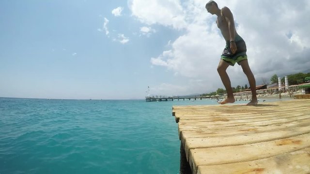Young sportive man diving from a wooden platform cheery in Egypt on a sunny day