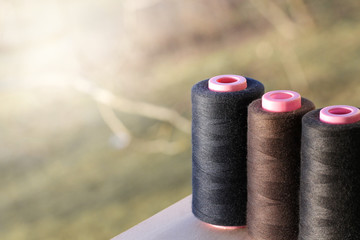 The creative background with spools of thread of three dark colors.