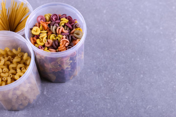 Multicolored pasta with the addition of natural vegetable dye. In a jar on a concrete table. Top view, copy Space.