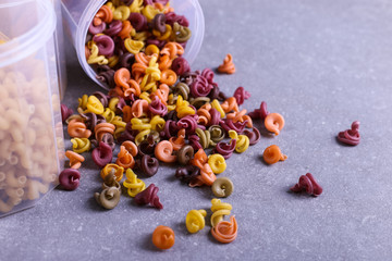 Multicolored pasta with the addition of natural vegetable dye. Scattered from a can on a concrete table. Top view, copy Space.