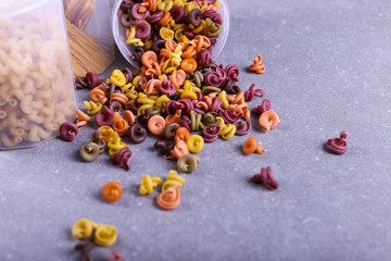 Multicolored pasta with the addition of natural vegetable dye. Scattered from a can on a concrete table. Top view, copy Space.