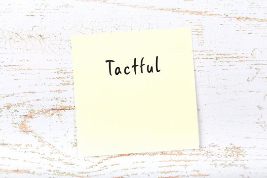 Yellow sticky note with handwritten word tactful