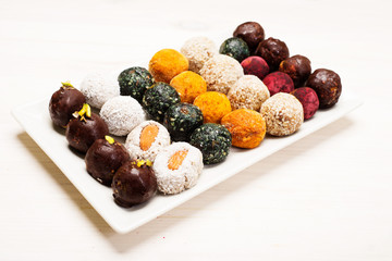 Raw useful vegan candy on a white rectangular plate on a white background. Homemade diet sweets