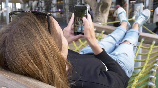 having rest in city hammock, woman take selfie of legs