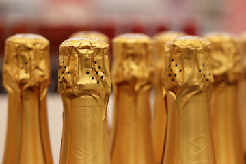 Fototapeta na wymiar Sparkling wine in golden foil for celebration. Champagne bottles in wine store
