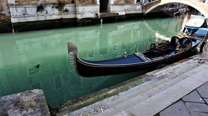 In the narrow canal of Venice there is a gondola waiting for the next couple in love