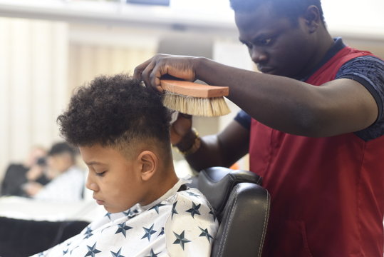 Boy in the african barbershop. Cute mixed boy makes a haircut in the African salon. Hair style. Haircut by machine for children. School boy hair style. 