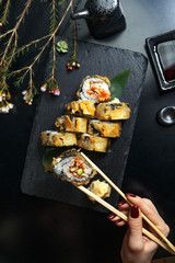 Fresh sushi rolls on black slate. Restaurant table setting.