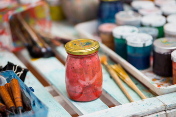 Jars of paint are on the table next to brushes for painting with Ebru technique