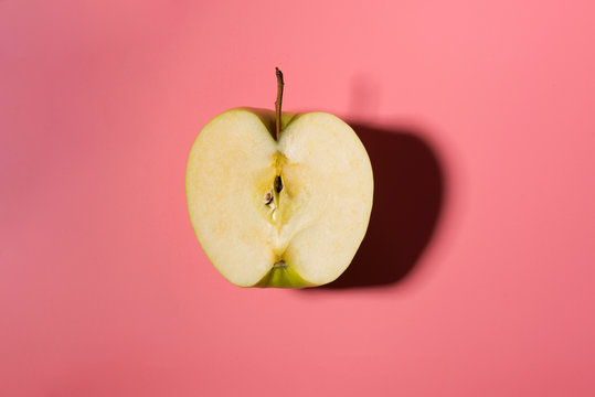 Sliced green delicious apple isolated on pink background with contrast shadows