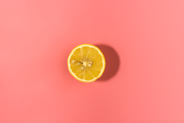 Sliced lemon on pink background with contrast shadow