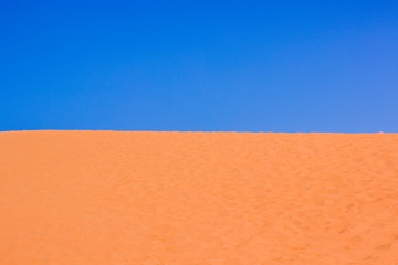Fototapeta premium idyllic picturesque vivid colorful simple landscape of Sahara desert with bright yellow sand dunes and empty blue sky, wallpaper pattern background photography concept with empty copy space for text 