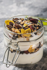 Glass full of white yogurt and muesli on light wooden board