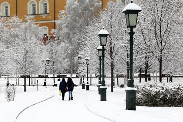 Snowfall in Moscow, people walking in Alexander garden during blizzard. Winter landscape with snow...