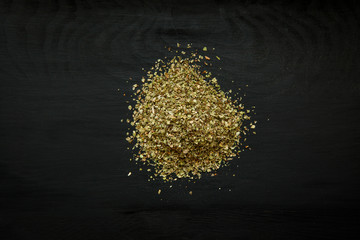 Close-up image of dry marjoram on black wood background, view above