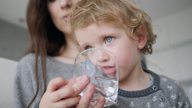 Cute Little Baby Boy At Home Drinking Clean Fresh Water From A Glass Cup Closeup