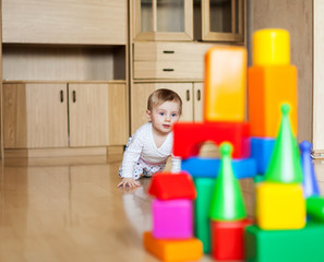 small child of 9 months playing on   floor of house.