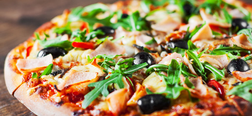 Pizza with Mozzarella cheese, mushrooms, ham, tomato sauce, pepper, olives, Spices and Fresh arugula. Italian pizza on wooden table background