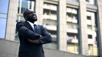 Successful architect crossed arms looking up at finished building, professional