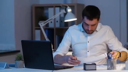 business, deadline and people concept - businessman with laptop computer and papers working late at night office - Powered by Adobe