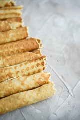 Waffle rolls, tasty and fragrant, with boiled condensed milk on a concrete background