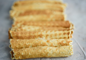 Waffle rolls, tasty and fragrant, with boiled condensed milk on a concrete background