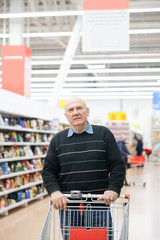 Aged man with   trolley buying groceries in   store