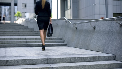 Woman in business suit going upstairs, climbing career ladder, achieving goals