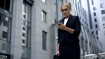 Fototapeta premium Businesswoman watching deal online via smartphone, worrying about investments