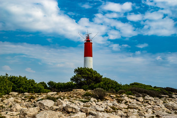 Rot weiss gestreifter Leuchtturm am Cap Couronne mit Felsen im Vordergrund und malerischem blauen...