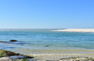 Beach with rocks, lake and turquoise water. White sand, dunes and blue sky. Playa de Carnota, Coruña, Spain.