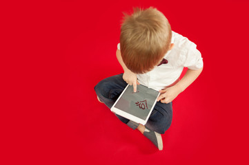 child boy is drawing in tablet ipad red heart on red background. Family and love relationship concept