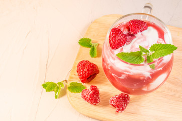 glass of raspberry yogurt with mint/yogurt with raspberry and mint on a wooden tray, closeup. Healthy breakfast. Top view and copy space